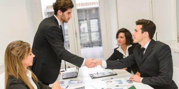 People seating in a room where two man shaking hands