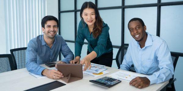 Three smiling mix raced professionals discussing new project at conference table