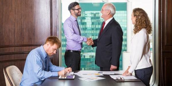 Businessmen shaking hands while another is writing