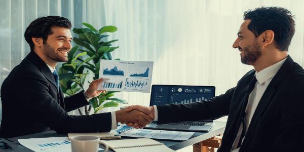 Two men shaking hands with a graph on the table