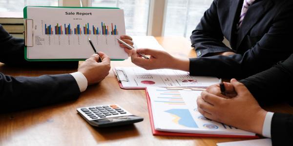 Midsection of businessman and colleague working over graph on table