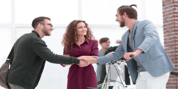 Three people talking and two men shaking hands