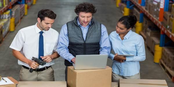 Warehouse workers and manager discussing with laptop