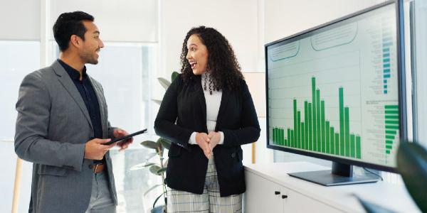 A woman showing the graph in a meating while a man hold tablet