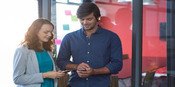 Male and female business executive using mobile phone and comminicating