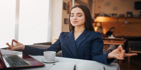 Calm and peaceful young business woman sit on table and meditation