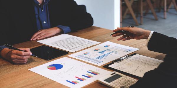 Midsection of male colleagues discussing charts on desk in office