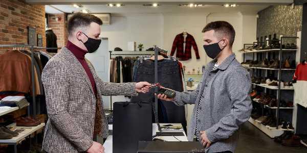 Man in face mask is using debit card to pay by wireless nfc technology for purchases in store