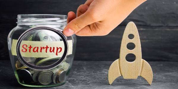 Glass jar rocket and the word startup the concept of raising funds for a startup