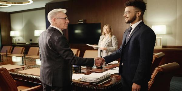 Caucasian and middle eastern men shaking hands standing in office boardroom
