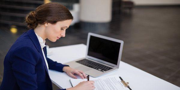 Businesswoman reading papers on clipboard and a pen in hand