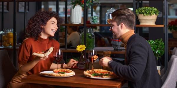 Young lovely couple is eating pizza it in pizzeria