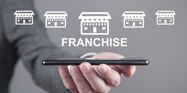Man holding smartphone with a franchise icons
