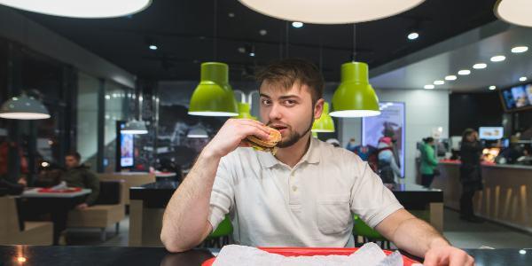 Man is sitting at a table in a fast swaddling restaurant, eating delicious food
