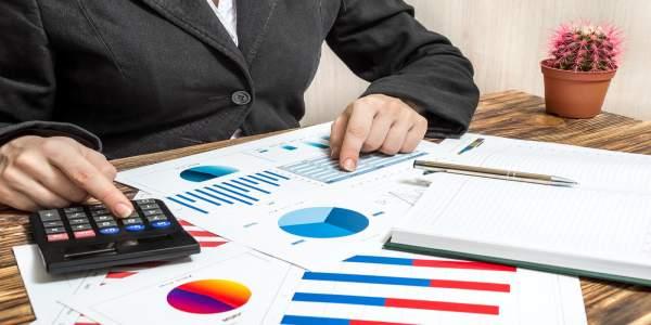 Businessman using calculator and charts on table