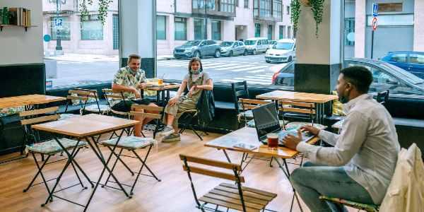 Young man working in coffee cafe talking to friends