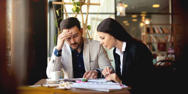 Two people solving business problems at the office and looking at documents