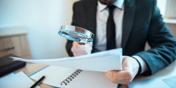 Man hand magnifier and document on table