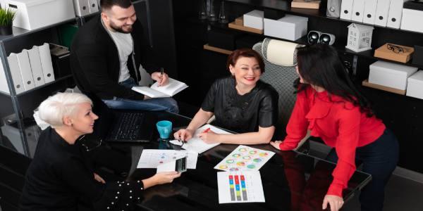 Smiling employees and employer talking in workplace